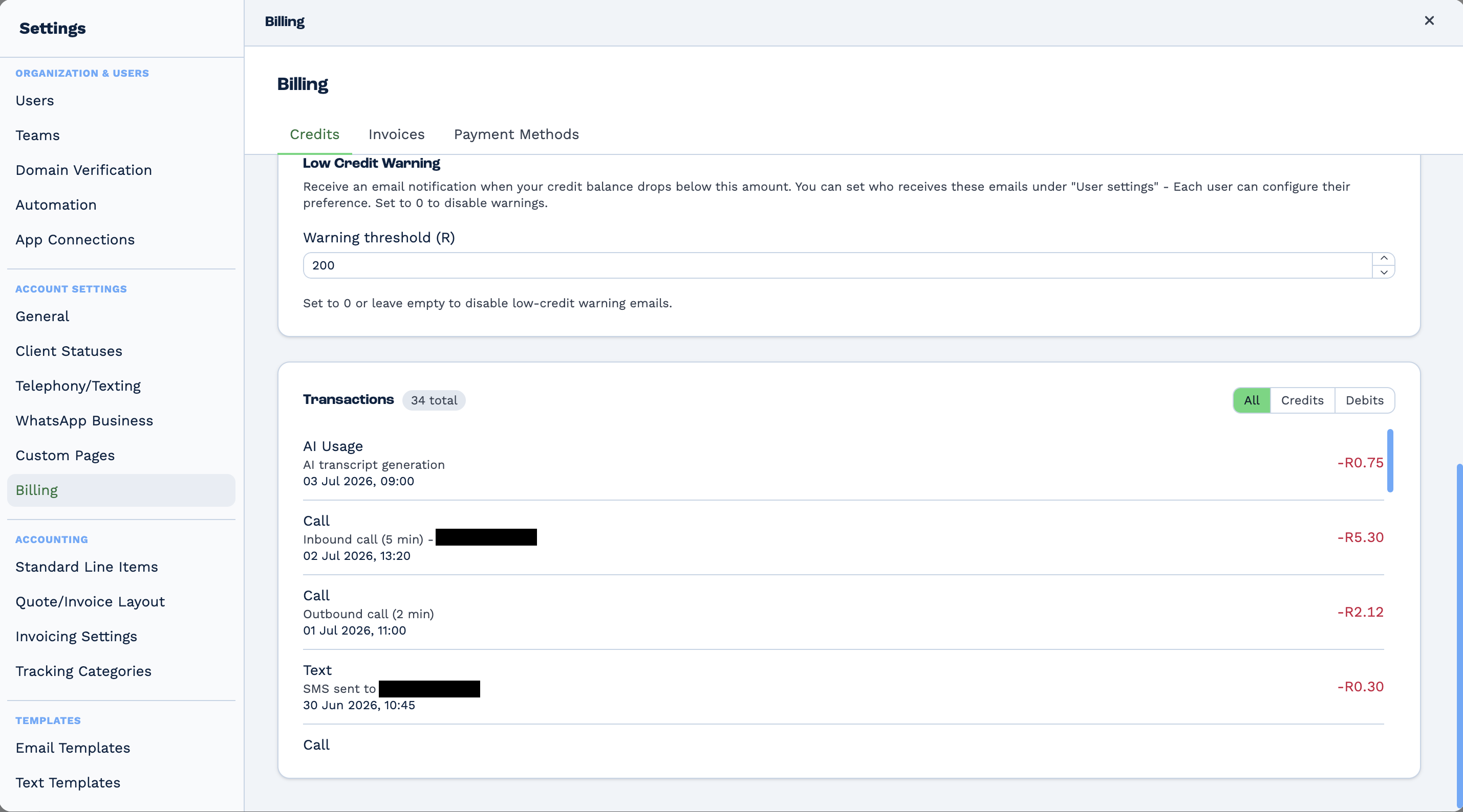 The lower half of the Credits tab. A Low Credit Warning section sets a warning threshold in rand and explains that recipients are configured per user and that zero disables the emails. Below it a Transactions list, filtered by All, Credits or Debits, shows a running history: an AI Usage entry for AI transcript generation, two Call entries for a five-minute inbound call and a two-minute outbound call, and a Text entry for an SMS — each with a date and a deduction in rand. The phone numbers in the inbound call and SMS entries are blacked out