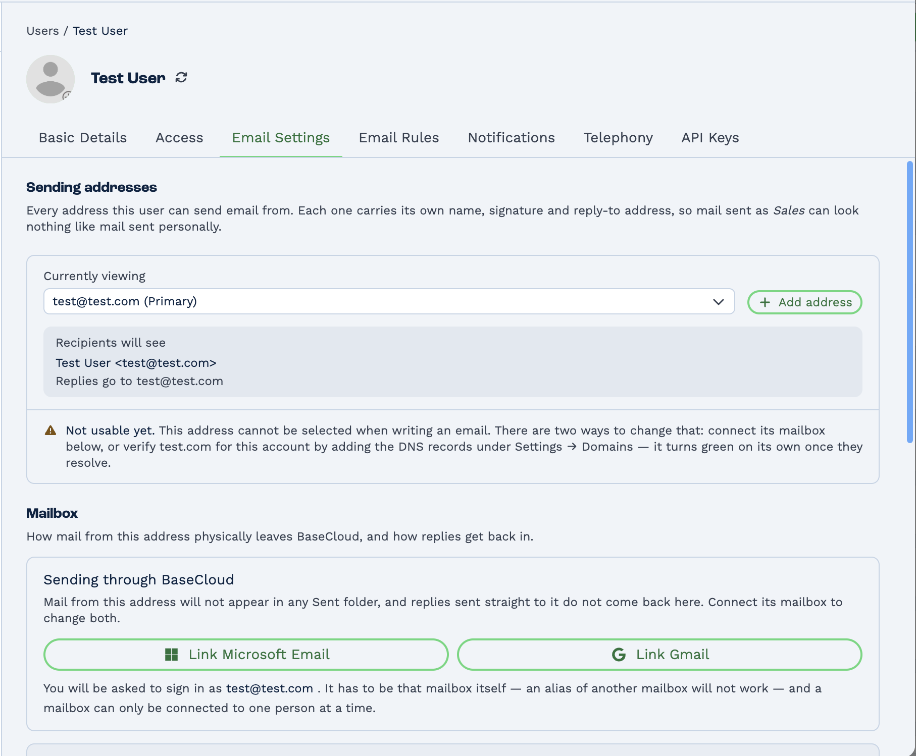 The Email Settings tab on a user's profile in BaseCloud. A Sending addresses section explains that every address carries its own name, signature and reply-to. A Currently viewing dropdown shows the primary address beside an Add address button, with a preview of what recipients will see. A warning reads "Not usable yet" and explains the address cannot be selected when writing an email until either its mailbox is connected or its domain is verified under Settings, Domains. Below, a Mailbox section offers Link Microsoft Email and Link Gmail buttons